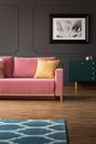 Fancy dresser with golden elements and a velvet pink sofa on hardwood floor in a vintage living room interior with gray walls. Rea Royalty Free Stock Photo