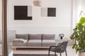 Fancy grey metal chair next to comfortable couch in bright living room