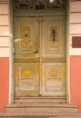 Fancy old green wooden doors with yellow design. Three stone steps leading up to doorway.