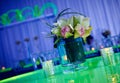 Fancy orchid cocktail flower arrangement and candles on green lucite table set up for a party top view with reflection Royalty Free Stock Photo