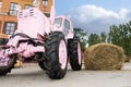 Fancy pink tractor next to a haystack