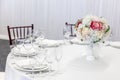 Fancy table set for dinner with flower composition in restaurant, luxury interior background. Wedding elegant banquet decoration Royalty Free Stock Photo