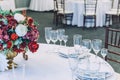 Fancy table set for dinner with flower composition in restaurant, luxury interior background. Wedding elegant banquet decoration Royalty Free Stock Photo