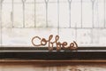 Fancy wire shaped into word COFFEE stand on the edge of window.