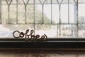 Fancy wire shaped into word COFFEE stand on the edge of window.