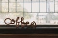 Fancy wire shaped into word COFFEE stand on the edge of window.