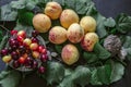 Apricots and colored cherries in a crystal plate on black plywood