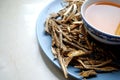 Bowl of brewed chinese herbs with dried assorted roots aside.