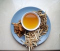 Bowl of brewed chinese herbs with dried assorted roots aside.