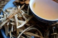 Bowl of brewed chinese herbs with dried assorted roots aside.