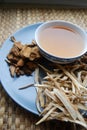 Bowl of brewed chinese herbs with dried assorted roots aside.