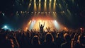 Fans in audience with hands raised on popular rock music concert listening to their favorite band performing on stage,