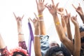 Fans gesturing horn sign with arms raised at music festival