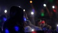 Fans Raise Hands and takes a photos in Front of Bright Colorful Strobing Lights at a concert in a night club.