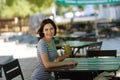 Positive girl with a smoothie. Smiling woman sitting at the blurred cafe background. Outdoors cafe concept. Copy space.