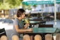 Positive girl with a smoothie. Smiling woman sitting at the blurred cafe background. Outdoors cafe concept. Copy space.