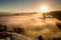 Fantastic dreamy sunrise on the top of the rocky mountain with the view into misty valley Royalty Free Stock Photo