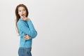 Fantastic european woman in cute blue sweater standing half-turned with surprised and tender expression, holding hand