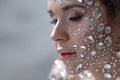 Fantastic fashion portrait of a young beautiful woman with transparent crystals on her face and shoulders.