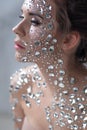 Fantastic fashion portrait of a young beautiful woman with transparent crystals on her face and shoulders.