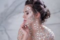 Fantastic fashion portrait of a young beautiful woman with transparent crystals on her face and shoulders.