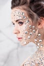 Fantastic fashion portrait of a young beautiful woman with transparent crystals on her face and shoulders. Royalty Free Stock Photo