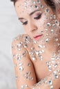 Fantastic fashion portrait of a young beautiful woman with transparent crystals on her face and shoulders.