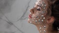 Fantastic fashion portrait of a young beautiful woman with transparent crystals on her face and shoulders.