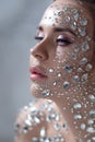 Fantastic fashion portrait of a young beautiful woman with transparent crystals on her face and shoulders.