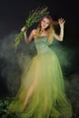 Fantastic girl in a long green dress in a fog