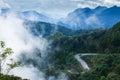 Fantastic mountain road in the mist, aerial view of curve asphalt road and two cars driving to the mountains peak, majestic blue