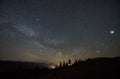 Fantastic mountains view at night. Fir-trees silhouettes against dark blue sky with sparkling stars Royalty Free Stock Photo