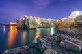 Fantastic night scene at Cala Paura gulf with Bastione di Santo Stefano in village on the rocks Polignano a Mare