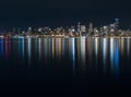 Fantastic nighttime panoramic city view with illuminated skyscrapers reflected on calm water.