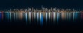 Fantastic nighttime panoramic city view with illuminated skyscrapers reflected on calm water.