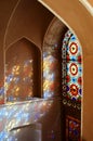 Old door with colored glass and reflected light on the thatched wall inside Dolatabad Garden, Yazd, Iran