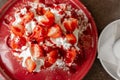 Fantastic Pavlova dessert with cream and strawberries served on red plate