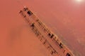 A fantastic pink-orange salt lake with salt crystals on wooden pillars stretching into the distance. Shooting from a drone. Royalty Free Stock Photo
