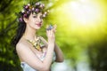 Fantastic Portrait of Sensual Brunette Female in White Dress Outdoors. Posing with Flowery Chaplet and Butterfly Against Sunlight