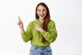 Fantastic promo ahead. Smiling redhead teen girl shows information, pointing left at advertisement and looking happy Royalty Free Stock Photo