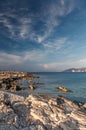 Fantastic rocky beach coastline during sunset. impressively beautiful seascape with picturesque sky over calm blue ocean under Royalty Free Stock Photo