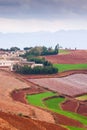 Fantastic scenery rural of south Yunnan, China. Beautiful wheat fields on the Red Land of Dongchuan. Old village and mountains Royalty Free Stock Photo