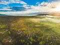 Fantastic shot of farm fields covered in early morning fog during sunrise