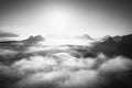 Fantastic sunrise on the top of the rocky mountain with view into misty valley. Black and white Royalty Free Stock Photo