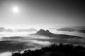 Fantastic sunrise on the top of the rocky mountain with view into misty valley. Black and white Royalty Free Stock Photo