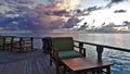 Fantastic sunset in the Maldives. On a wooden platform in the ocean are tables and chairs. Royalty Free Stock Photo