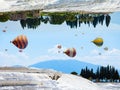 Fantastic unreal world, hot air balloons fly in blue sky between white Pammukale travertines, Turkey