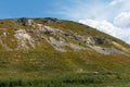 Fantastic view from below of the hill and clouds on a summer\'s day. Grass and many stones grow on hill Royalty Free Stock Photo