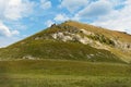 Fantastic view from below of hill and clouds on a sunny day. Grass, trees and many stones grow on hill. Small stones pour down in Royalty Free Stock Photo