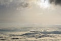 Fantastic wide top view of mountain valley filled with white puffy like snow clouds and fog stretching to horizon under bright mo Royalty Free Stock Photo